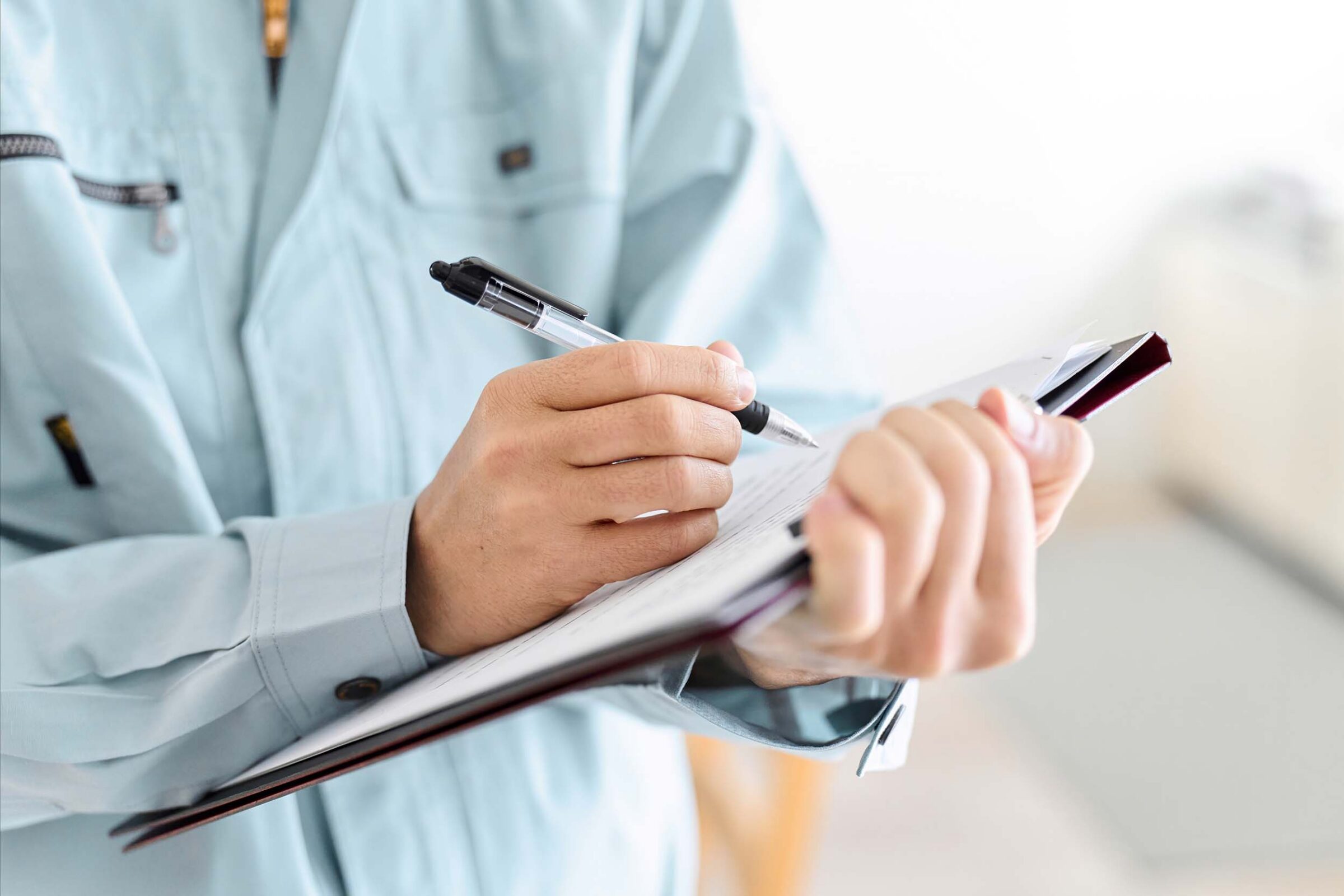 Hands of employee filling out a checklist on a clipboard